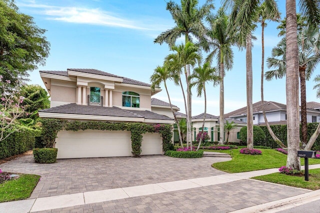 mediterranean / spanish house with an attached garage, a tiled roof, decorative driveway, and stucco siding