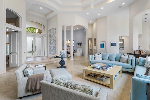 living area featuring a towering ceiling, ornate columns, arched walkways, and recessed lighting