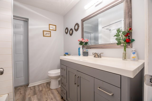 bathroom with baseboards, vanity, toilet, and wood finished floors