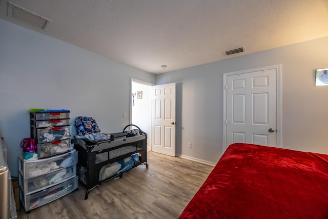 bedroom featuring wood finished floors, visible vents, and baseboards