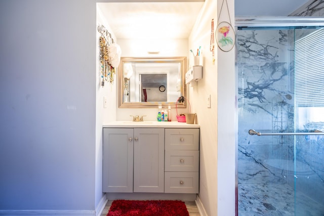 full bath featuring a shower stall, vanity, and baseboards