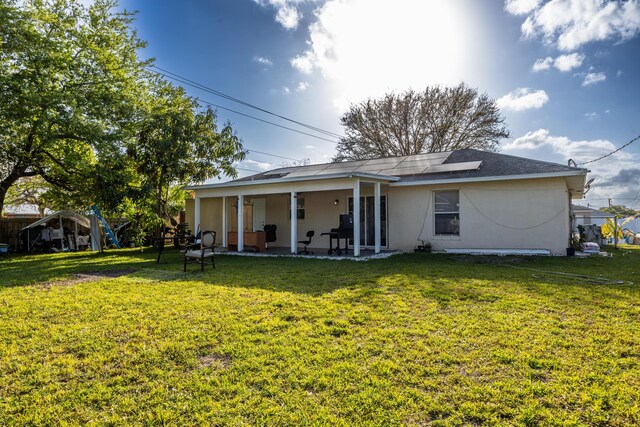 back of property with a lawn, a patio area, fence, and stucco siding