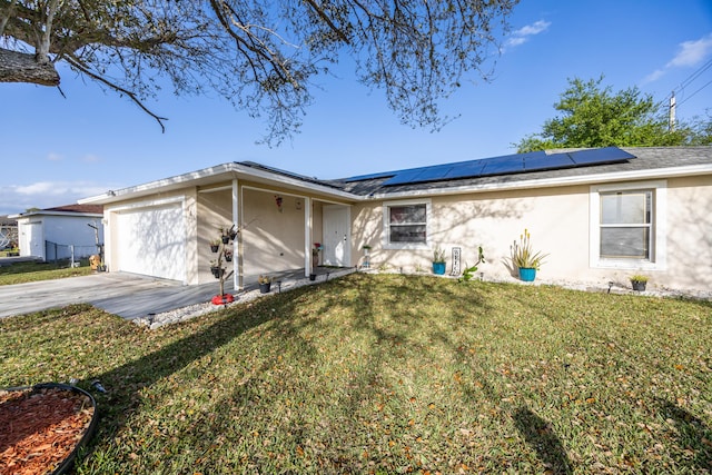 single story home with solar panels, stucco siding, concrete driveway, an attached garage, and a front yard