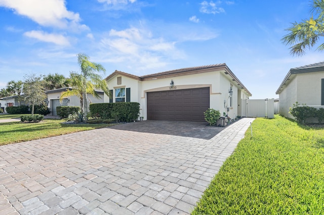 ranch-style house featuring a garage, a gate, decorative driveway, a front lawn, and stucco siding