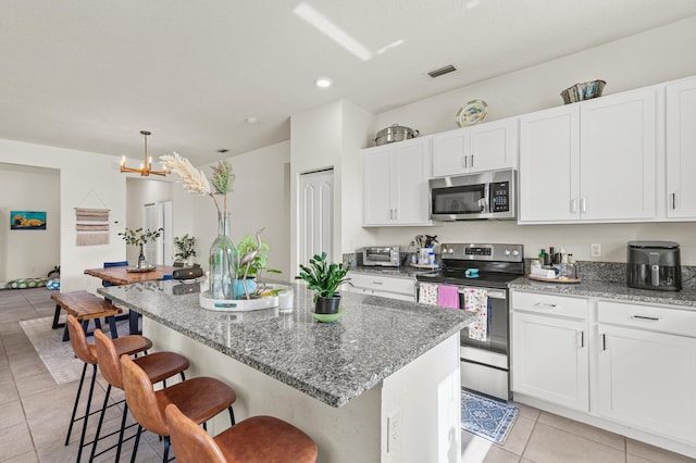 kitchen with white cabinets, light tile patterned floors, a kitchen bar, and stainless steel appliances