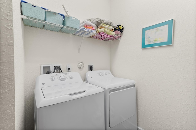 washroom featuring laundry area, a textured wall, and independent washer and dryer