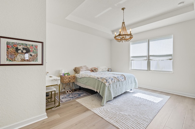 bedroom with a tray ceiling, wood finished floors, and baseboards