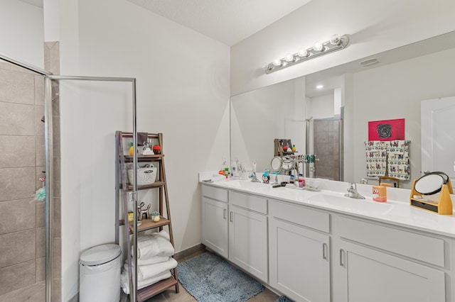 full bath with a stall shower, a sink, baseboards, and double vanity