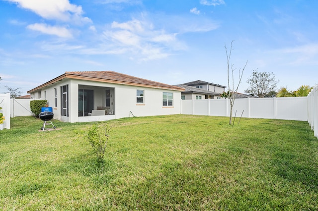 back of property featuring a lawn, a fenced backyard, a sunroom, and stucco siding