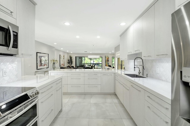 kitchen featuring a peninsula, appliances with stainless steel finishes, backsplash, and a sink