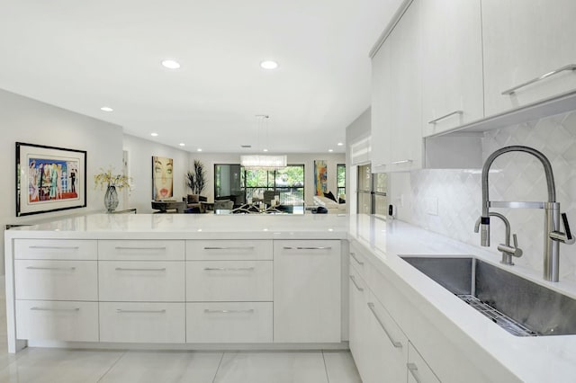 kitchen featuring a peninsula, modern cabinets, white cabinetry, and a sink