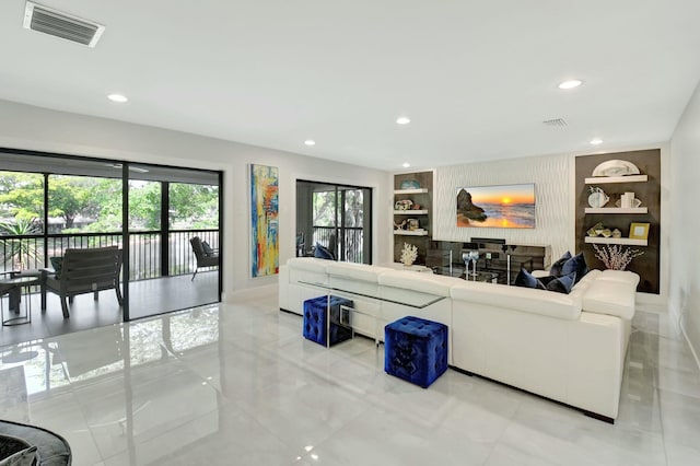 living area with baseboards, built in shelves, visible vents, and recessed lighting