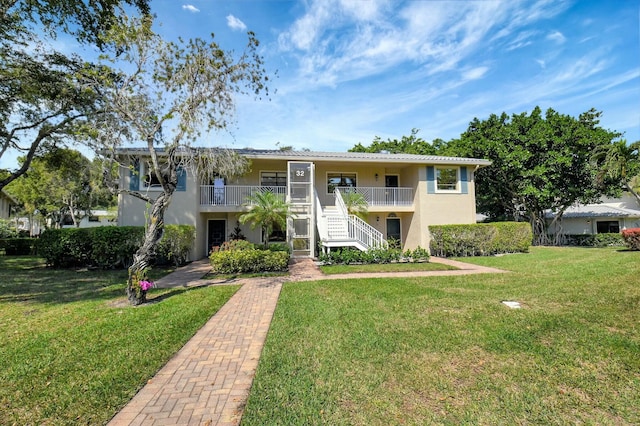 multi unit property featuring stairway, a front lawn, and stucco siding