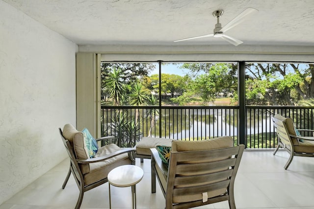 sunroom featuring a water view and a ceiling fan