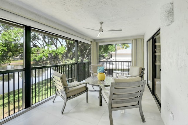 sunroom / solarium featuring ceiling fan and a water view