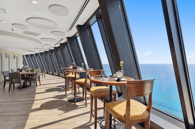 dining area with light wood-type flooring, a water view, and visible vents