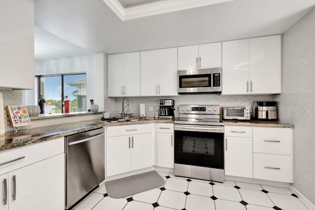 kitchen featuring light floors, stainless steel appliances, ornamental molding, white cabinets, and a sink