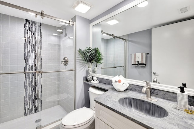 full bathroom featuring toilet, a shower stall, visible vents, and vanity