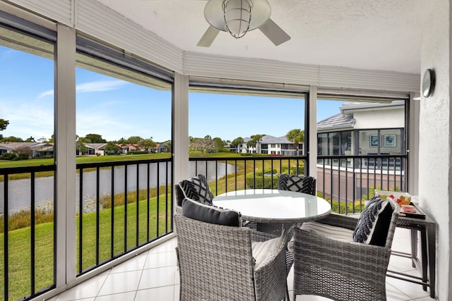 sunroom featuring a water view and ceiling fan