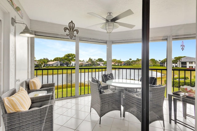 sunroom / solarium with a ceiling fan and a water view