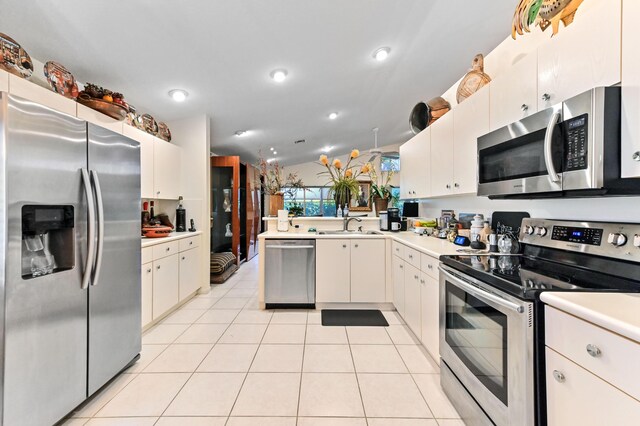 kitchen featuring a peninsula, light tile patterned floors, appliances with stainless steel finishes, and light countertops