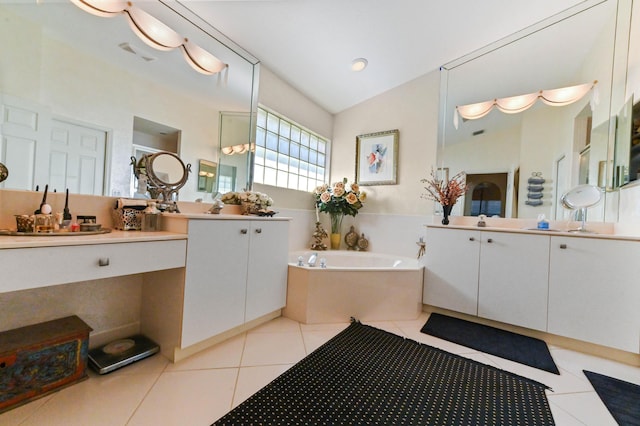 bathroom with lofted ceiling, two vanities, tile patterned floors, a garden tub, and a sink