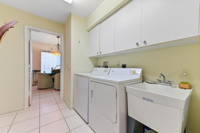 laundry area featuring light tile patterned floors, a sink, baseboards, independent washer and dryer, and cabinet space