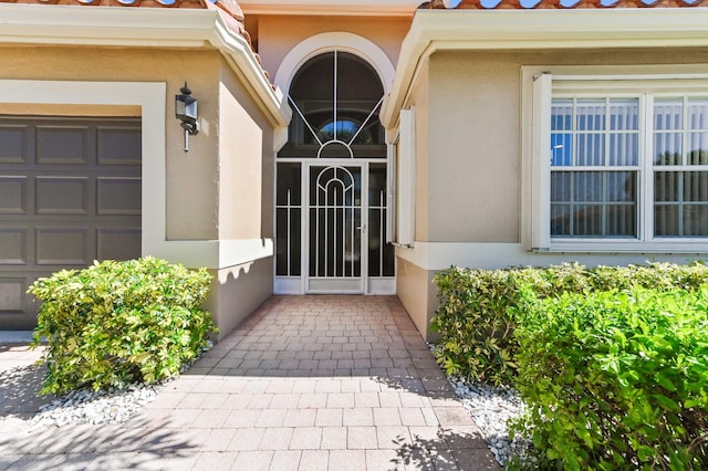 doorway to property with a garage and stucco siding