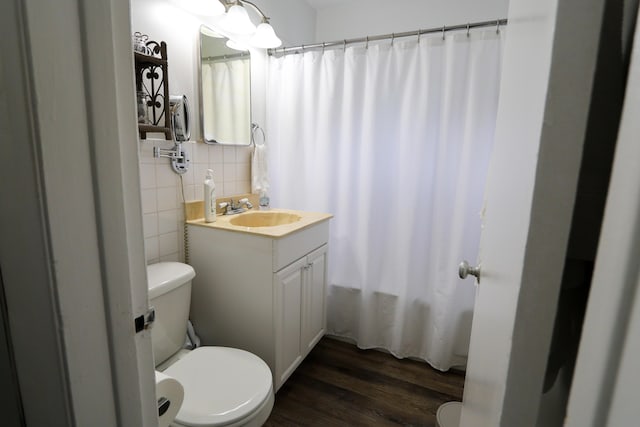 bathroom with toilet, wood finished floors, tile walls, and vanity