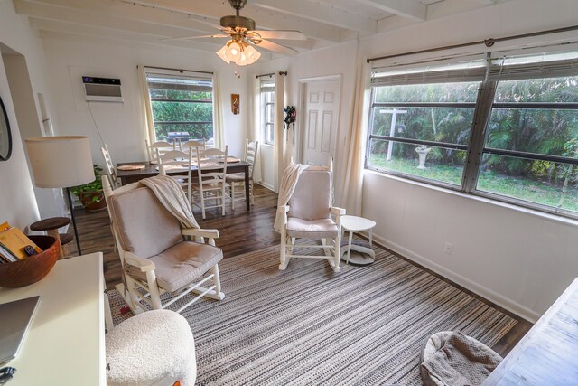 sitting room featuring wood finished floors, a ceiling fan, baseboards, an AC wall unit, and beam ceiling