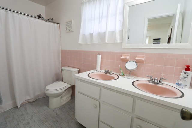 bathroom with a sink, tile walls, toilet, and double vanity