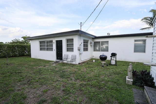 rear view of house with a lawn and stucco siding