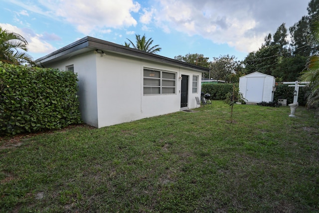 view of property exterior featuring a storage shed, a lawn, an outdoor structure, and stucco siding