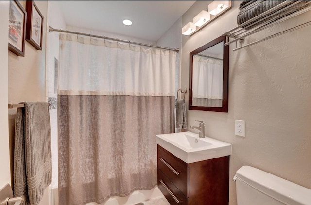 full bathroom with vanity, shower / bath combination with curtain, toilet, and a textured wall