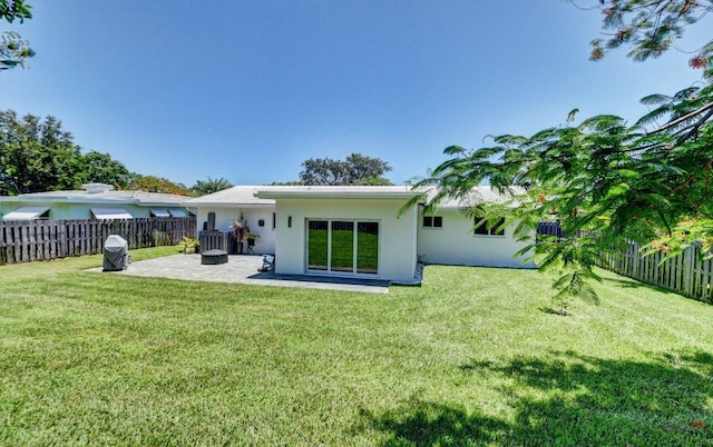 rear view of property featuring a yard, a patio area, a fenced backyard, and stucco siding