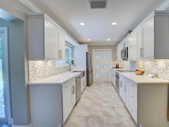 kitchen with visible vents, light countertops, appliances with stainless steel finishes, crown molding, and tasteful backsplash