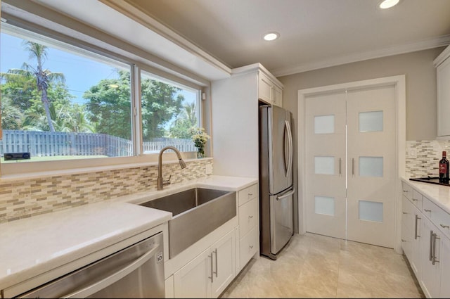 kitchen featuring a sink, ornamental molding, light countertops, stainless steel appliances, and tasteful backsplash