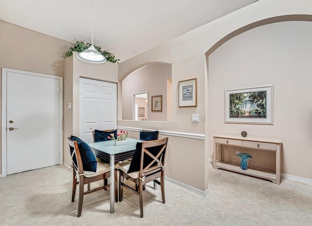 dining space featuring baseboards and arched walkways