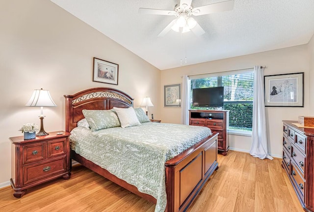 bedroom with lofted ceiling, light wood-style flooring, baseboards, and a textured ceiling