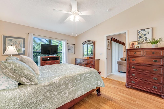 bedroom with lofted ceiling, light wood-style floors, a ceiling fan, a textured ceiling, and baseboards