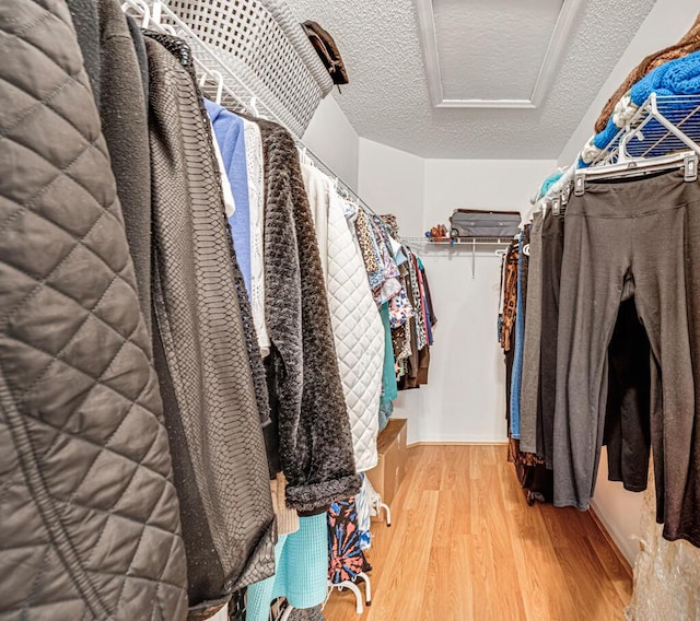 walk in closet with attic access and wood finished floors