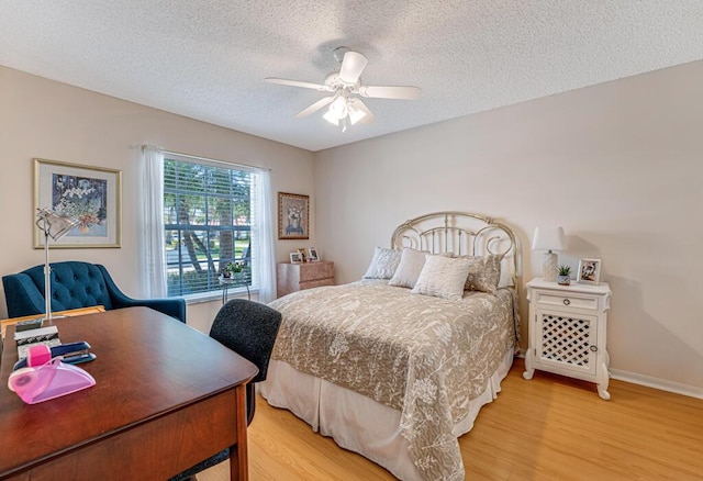 bedroom with a textured ceiling, light wood finished floors, a ceiling fan, and baseboards