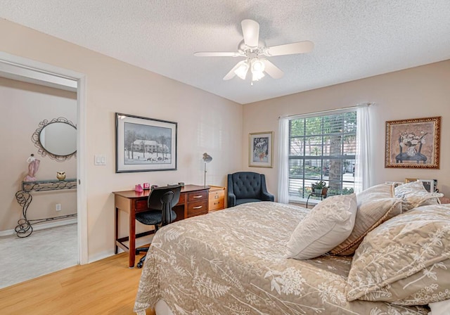 bedroom featuring a ceiling fan, baseboards, a textured ceiling, and light wood finished floors