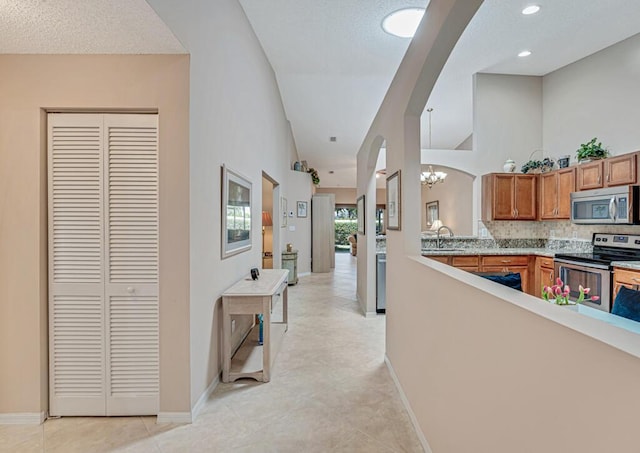 hall featuring high vaulted ceiling, arched walkways, a sink, and baseboards