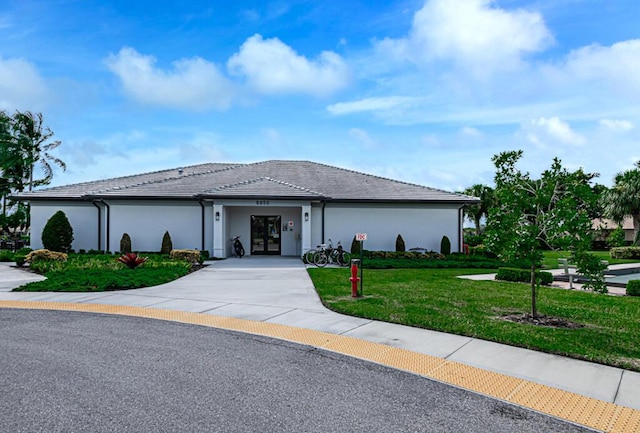 view of front of property with concrete driveway, a front yard, a tile roof, and stucco siding