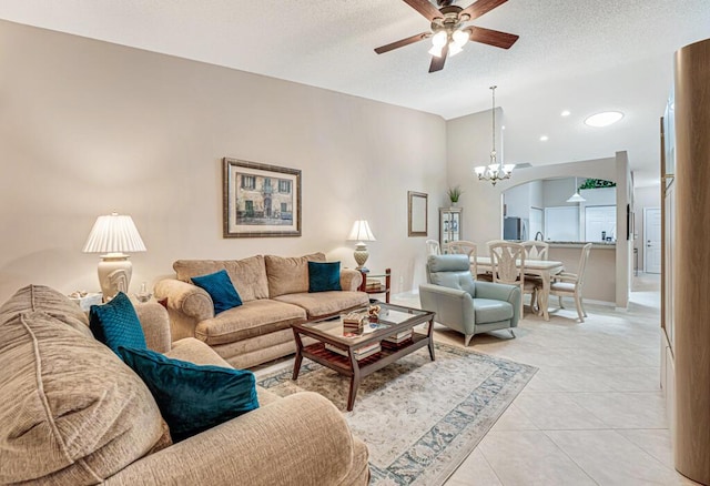 living area with light tile patterned floors, a textured ceiling, ceiling fan with notable chandelier, and baseboards