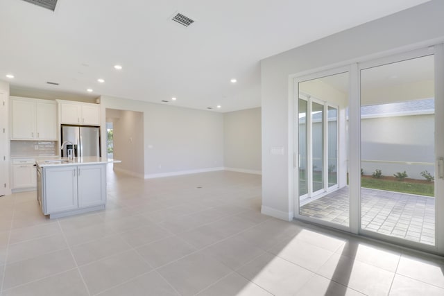 kitchen with light tile patterned floors, tasteful backsplash, visible vents, stainless steel fridge with ice dispenser, and light countertops