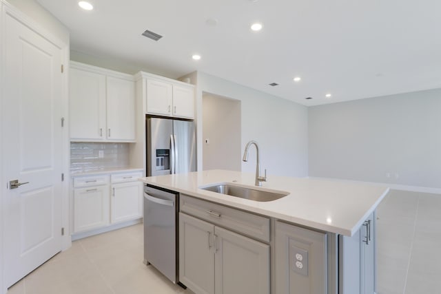 kitchen with a center island with sink, stainless steel appliances, visible vents, decorative backsplash, and a sink