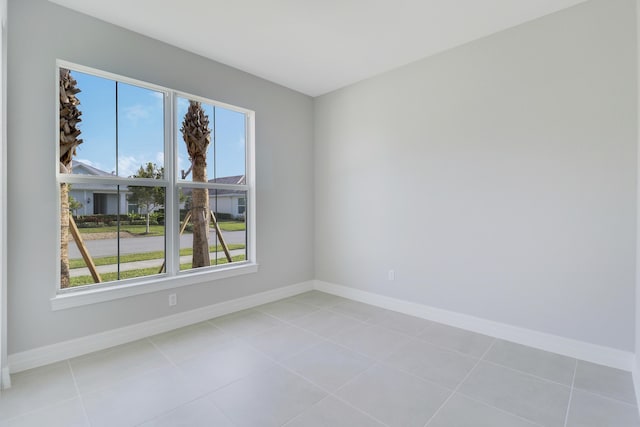 spare room featuring plenty of natural light, baseboards, and light tile patterned flooring