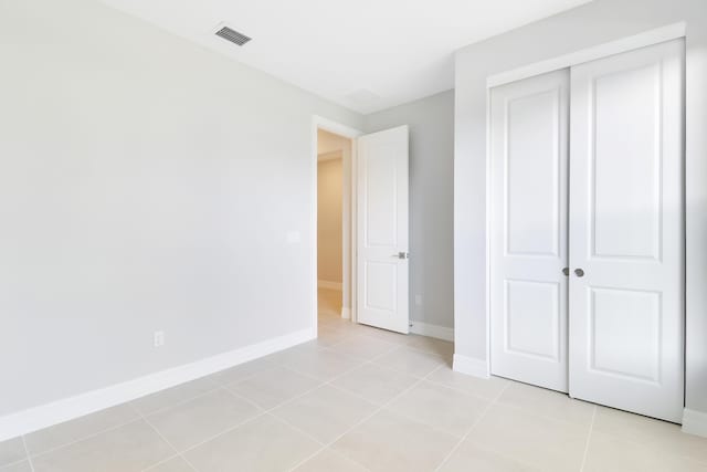 unfurnished bedroom with baseboards, visible vents, a closet, and light tile patterned flooring